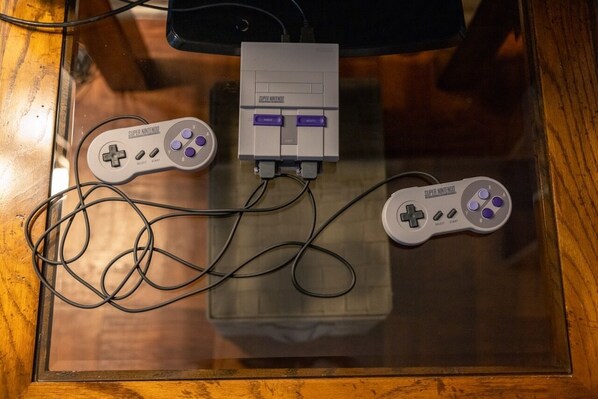 A glass table with two Super Nintendo controllers and a power adapter.
