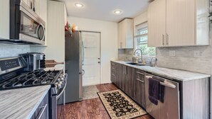 A modern kitchen with stainless steel appliances, wooden cabinets, and a marble countertop.