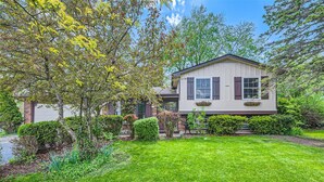 A two-story house with a well-maintained lawn and mature trees.