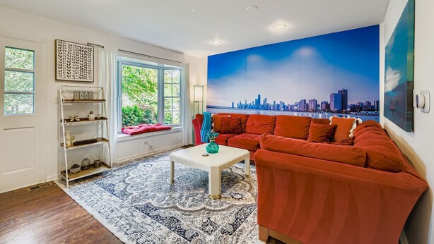 A living room with a cityscape mural, a red sofa, a white coffee table, and a patterned rug.