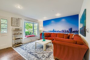 A living room with a cityscape mural, a red sofa, a white coffee table, and a patterned rug.