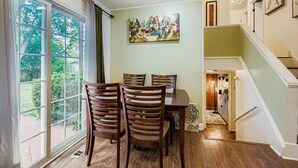 A dining area with a table and chairs, a painting on the wall, and a staircase leading to another level.