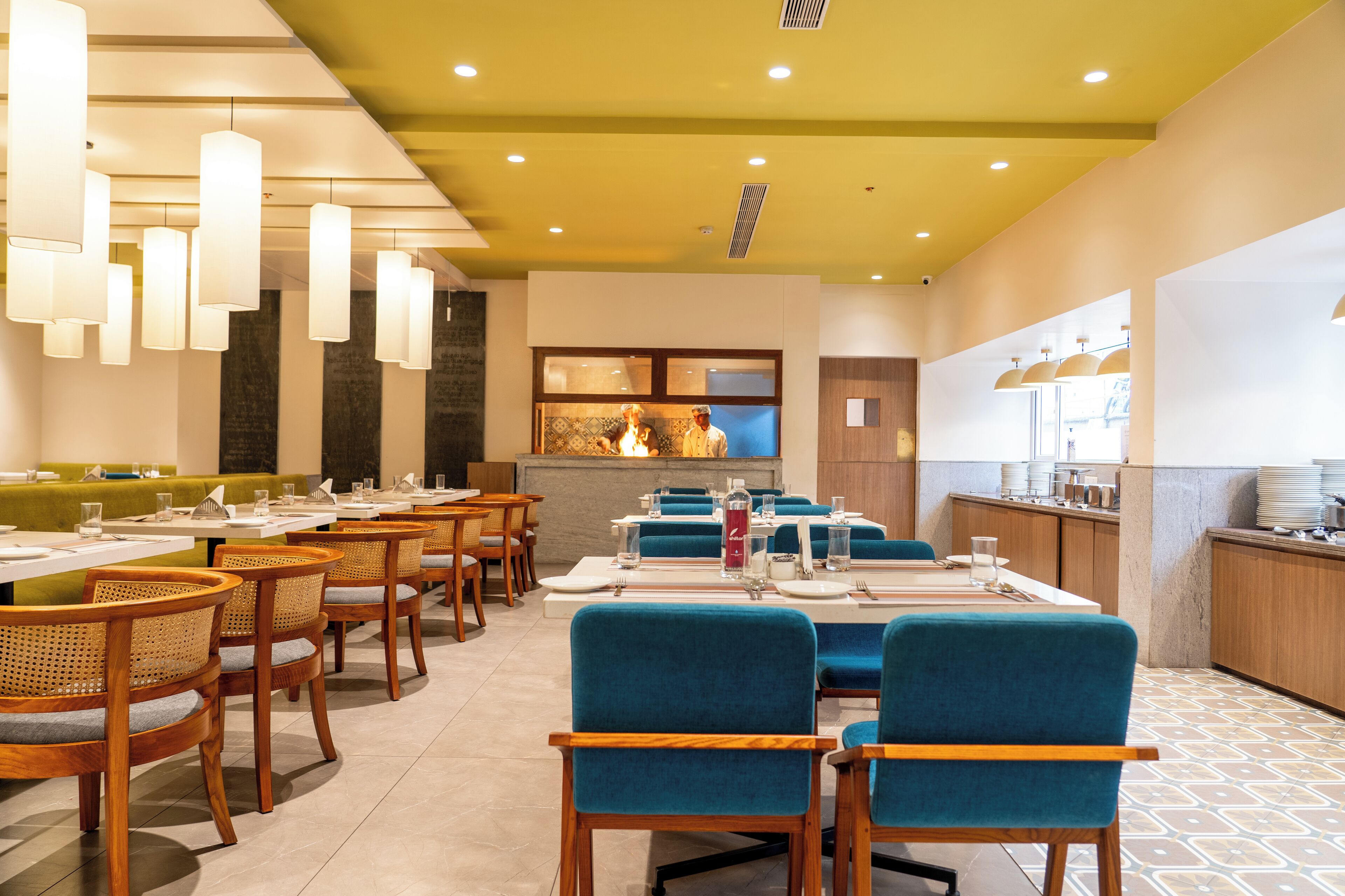 A restaurant with multiple dining tables, chairs, and a kitchen area.