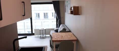 A compact kitchen with a dining area, a small table, and a sofa.