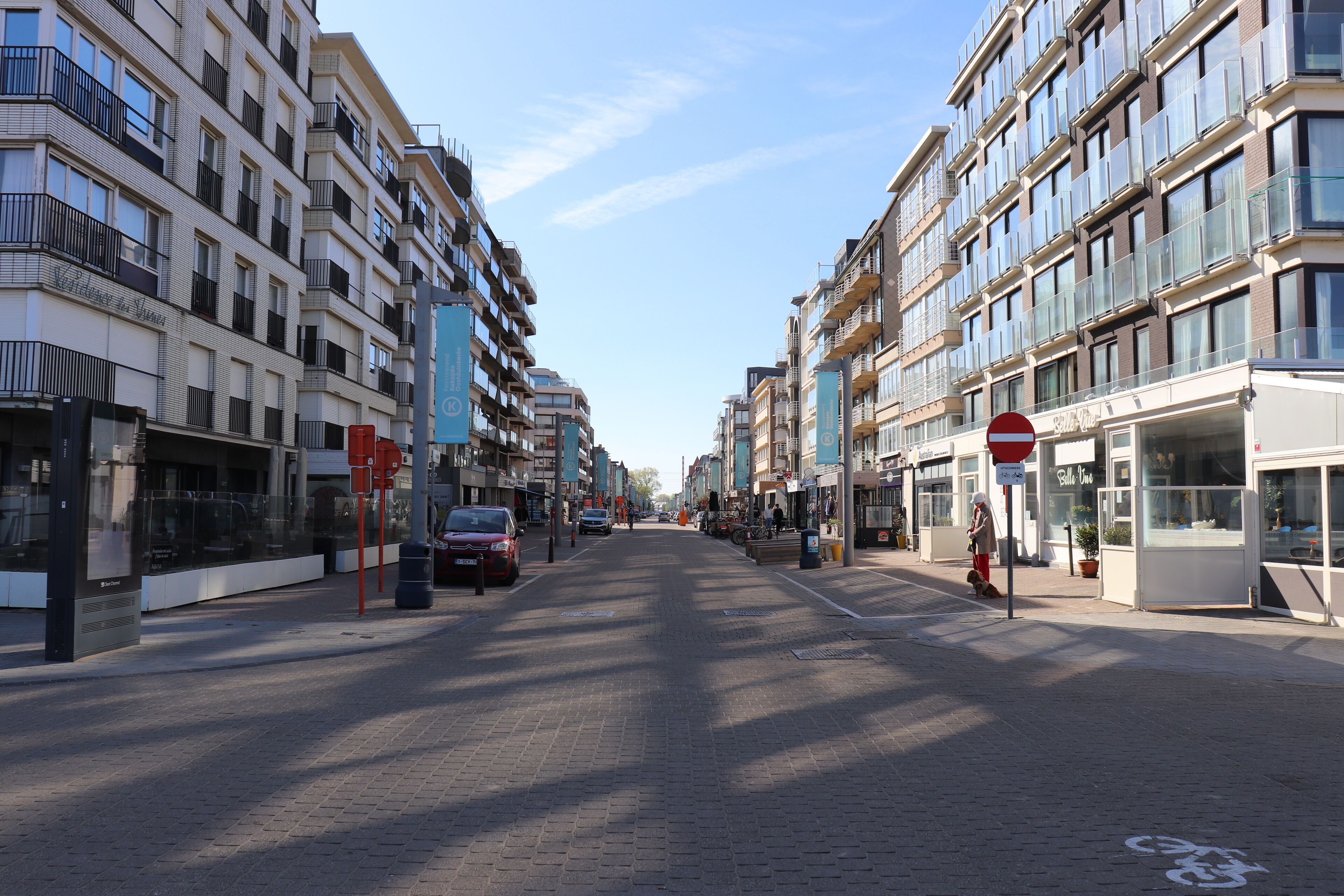 En gade med moderne bygninger, et fodgængerfelt og et forbudt-for-kørsel-skilt.