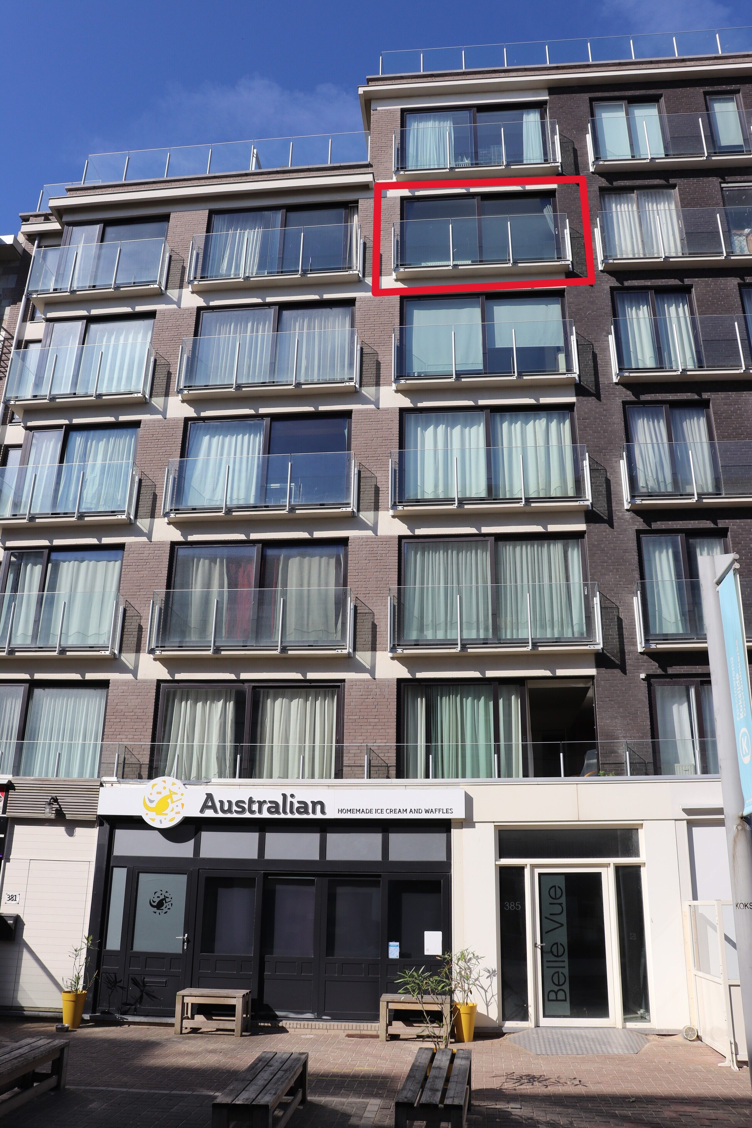 Un edificio a più piani con una serie di balconi e un negozio con scritto 'Australian'.