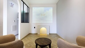 A modern interior with a fireplace, a projector screen displaying 'Smart Mirroring Air', and two armchairs.