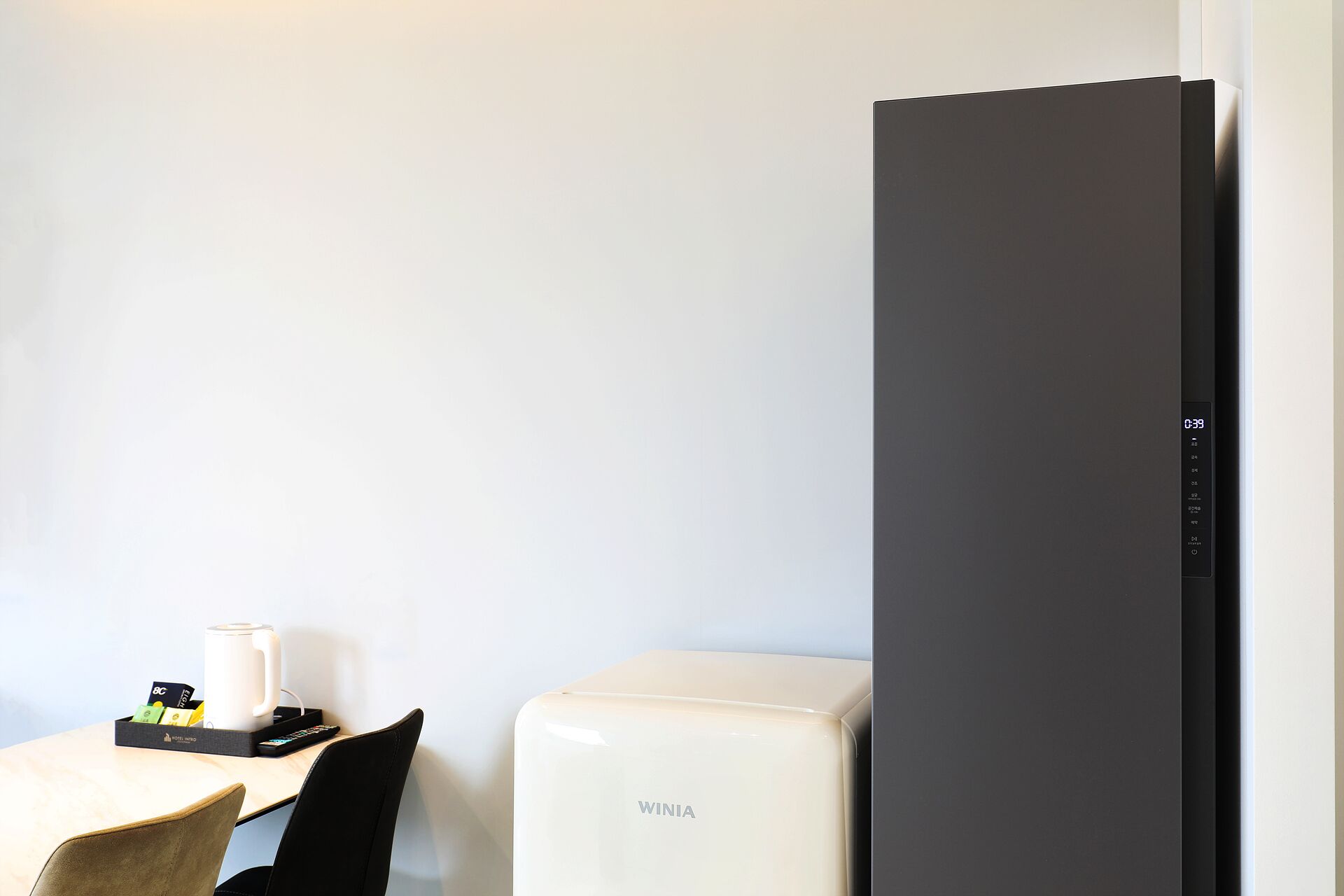 Quarto de hotel com minibar, máquina de café e geladeira preta.