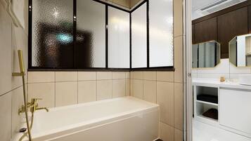 A modern bathroom with a bathtub, a glass shower enclosure, and a vanity with a mirror.