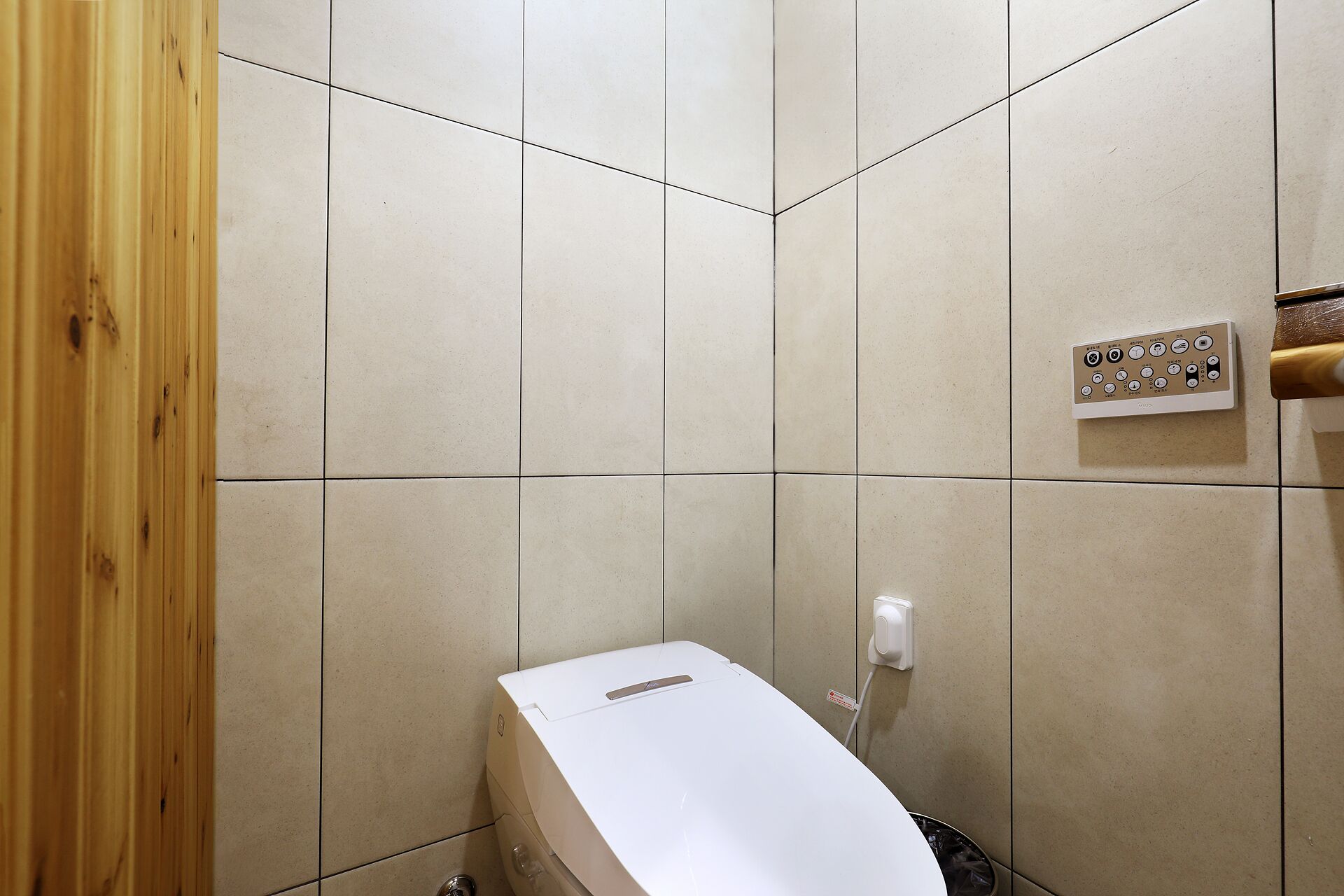 A bathroom with a toilet, a hand dryer, and a control panel.