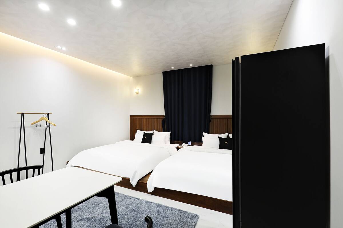 A hotel room with two beds, a desk, and a chair.