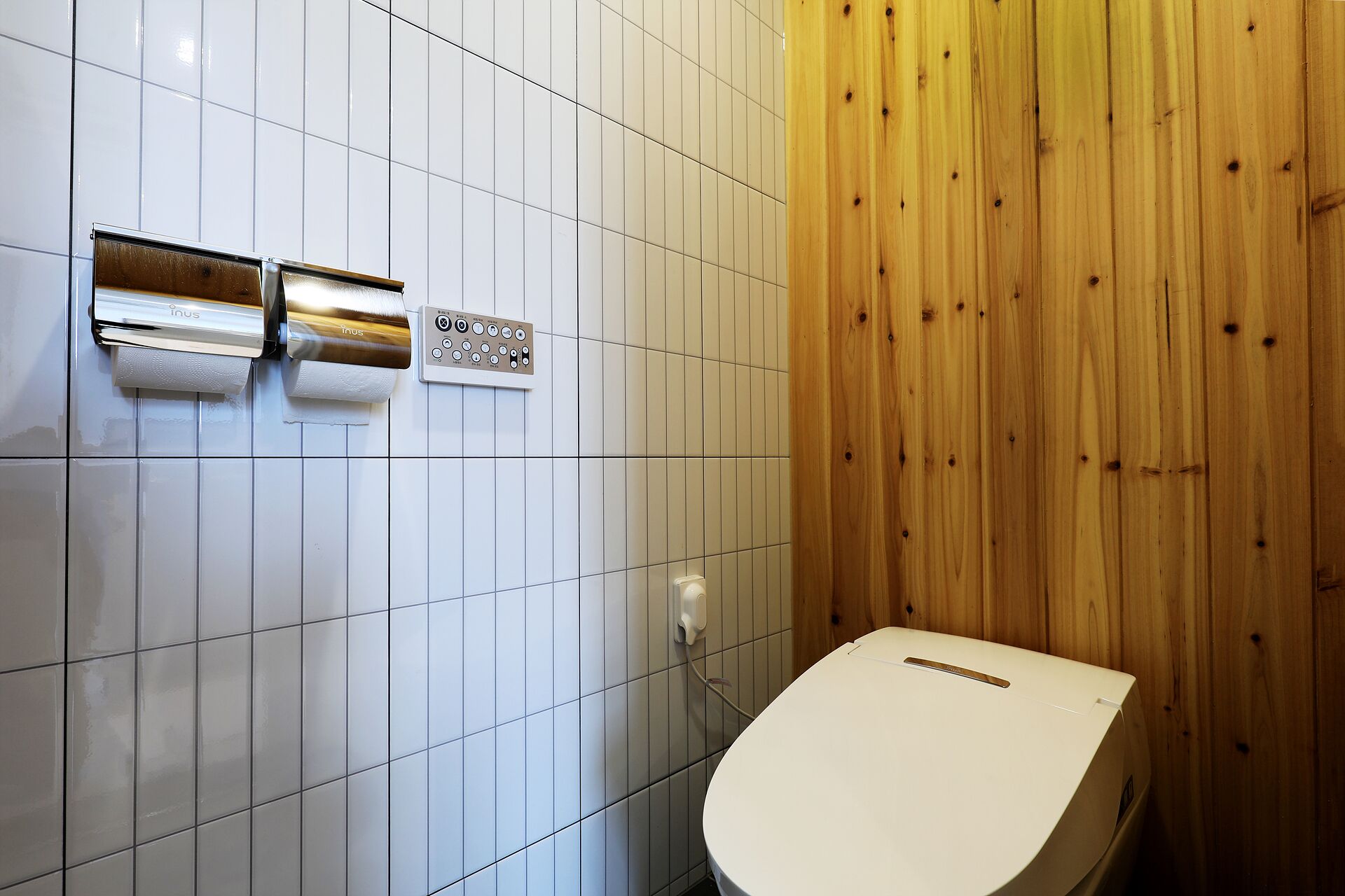 A bathroom with white tiled walls, a wooden panel wall, and a white toilet.