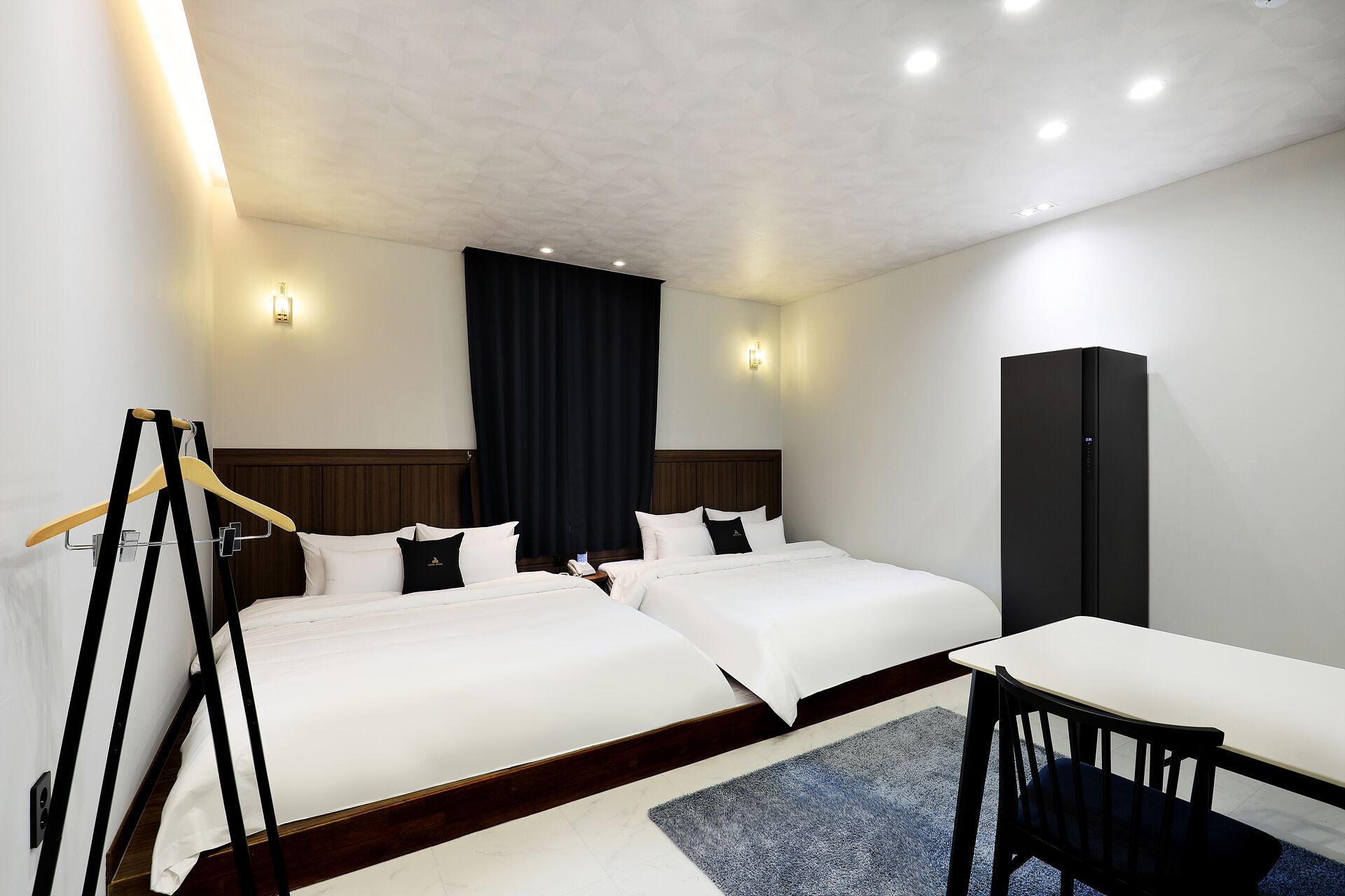 A hotel room with two beds, a desk, and a wardrobe.