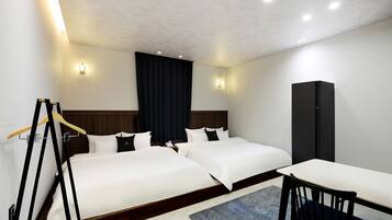 A hotel room with two beds, a desk, and a wardrobe.