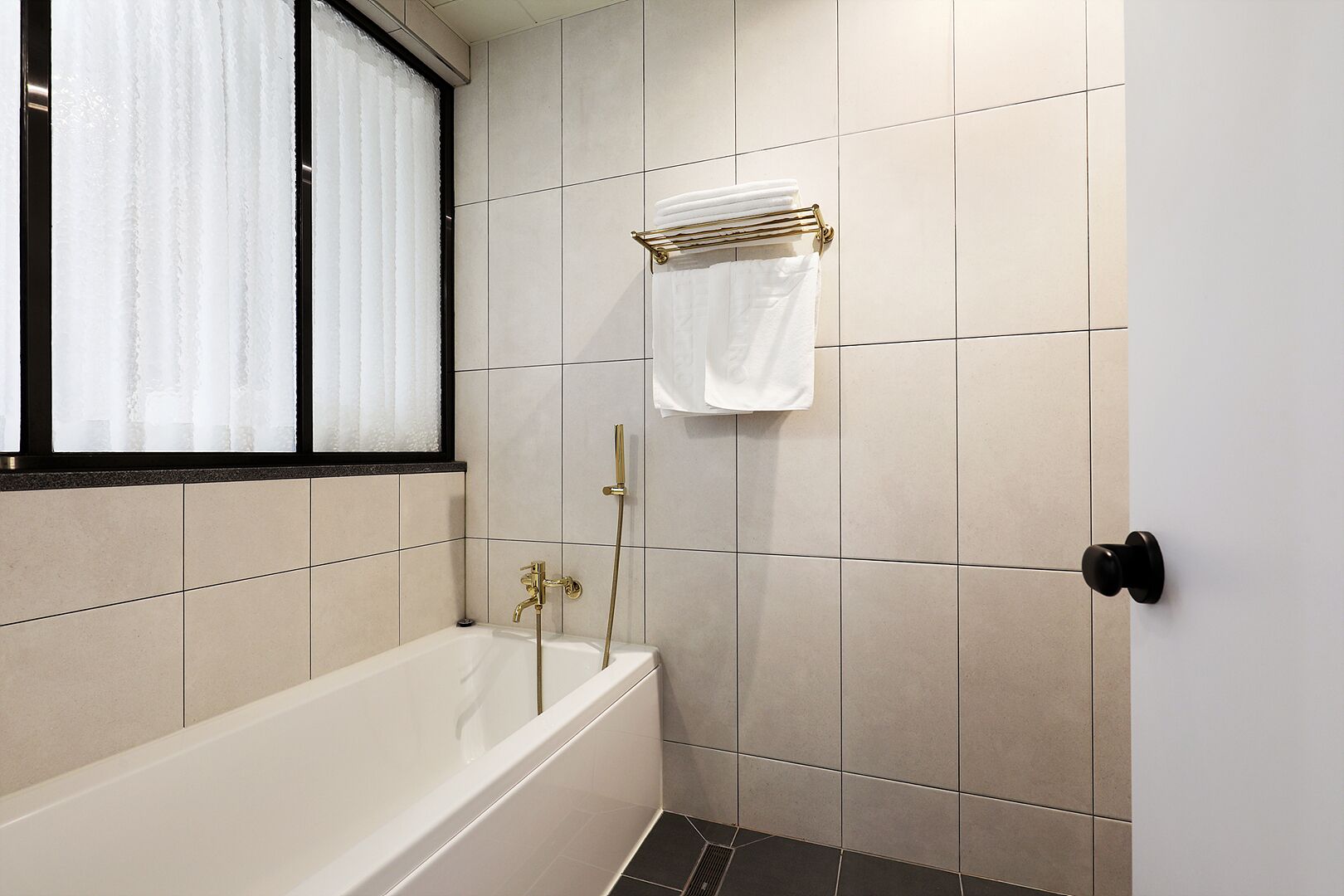 Een badkamer met een bad, een douche en een raam met gordijnen.