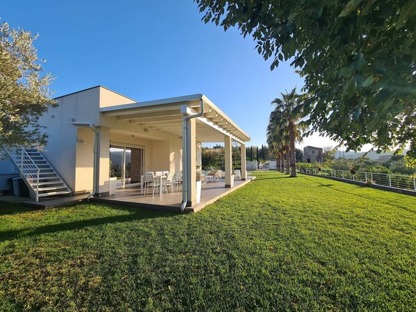 A modern house with a covered patio, a staircase, and a well-maintained lawn. - Holiday Home in Leonforte With Private Pool (Leonforte)