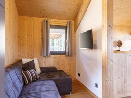Una habitación acogedora con un sofá modular, un televisor de pantalla plana en la pared y una ventana con cortinas.