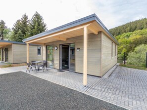 Een modern gebouw met een overdekte patio, een klein zitgedeelte buiten en een verharde looppad.