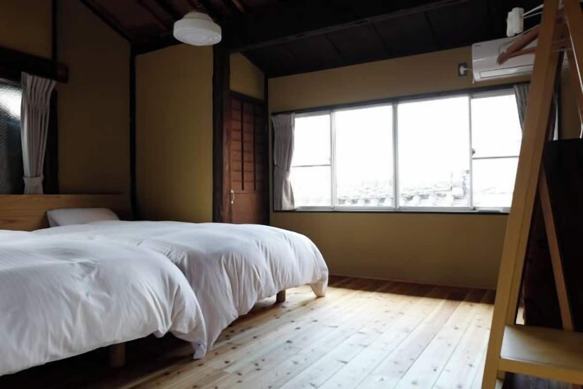 A room with a bed, a window, and a wooden floor.