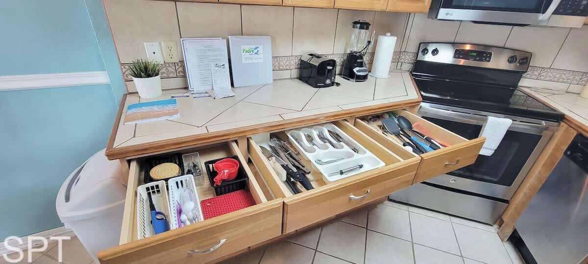 Une cuisine équipée d’un système de rangement intégré pour les tiroirs, d’une machine à café et d’un four à micro-ondes.
