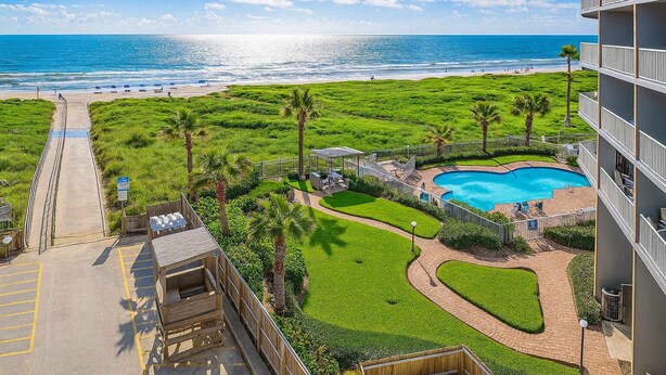 Um resort com piscina, vista para a praia e gramado bem cuidado.