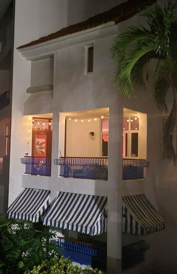A two-story building with balconies, a staircase, and string lights.