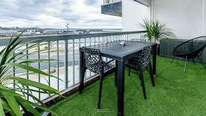 A balcony with a table and chairs, a potted plant, and a view of the sea and boats. - Appartement VUE MER (Quiberon)