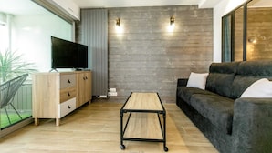 A modern living room with a flat-screen TV, a wooden cabinet, a sofa, and a coffee table. - Appartement VUE MER (Quiberon)
