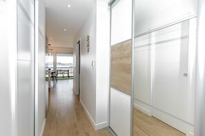 A modern hallway with a view to a balcony, wooden flooring, and a glass partition wall. - Appartement VUE MER (Quiberon)