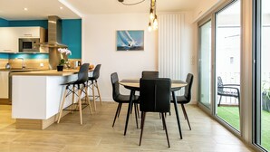 A modern kitchen with a central island, black chairs, and a dining table. - Appartement VUE MER (Quiberon)