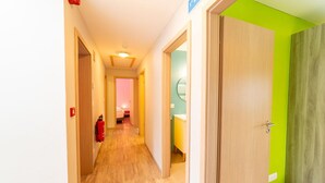 A hotel hallway with a fire extinguisher, a door with a green accent, and a visible bathroom with a sink and mirror. - Family Home, Kicker, Sunset Views (Trois-Ponts)
