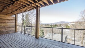 Eine Holzdar Terrasse mit Metallgeländer, mit Blick auf eine Wohngegend mit Häusern und Bäumen.