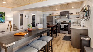 Una cucina moderna con soffitto in legno, elettrodomestici in acciaio inossidabile e un angolo bar con sgabelli.