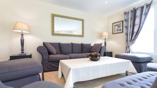 A modern living room with a grey sofa set, a white coffee table, and a small side table with a lamp.