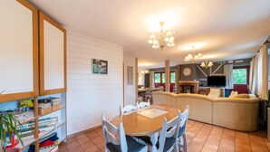Un comedor acogedor con una mesa de madera y sillas blancas, un sofá y una chimenea.