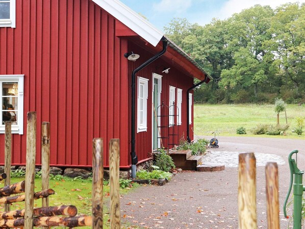 En rød træbygning med veranda og grusvej.
