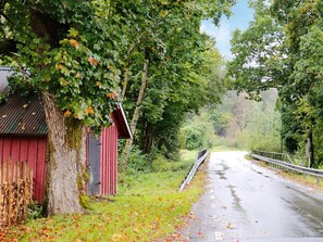 A rural road with a red barn and trees on either side. - 4 Star Holiday Home in Tvaaker (Tvaaker)