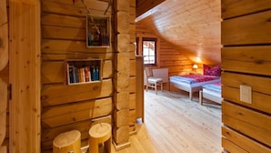 Ein gemütliches Blockhaus-Interieur mit einer Holzregal, einem kleinen Tisch und einem Sessel.
