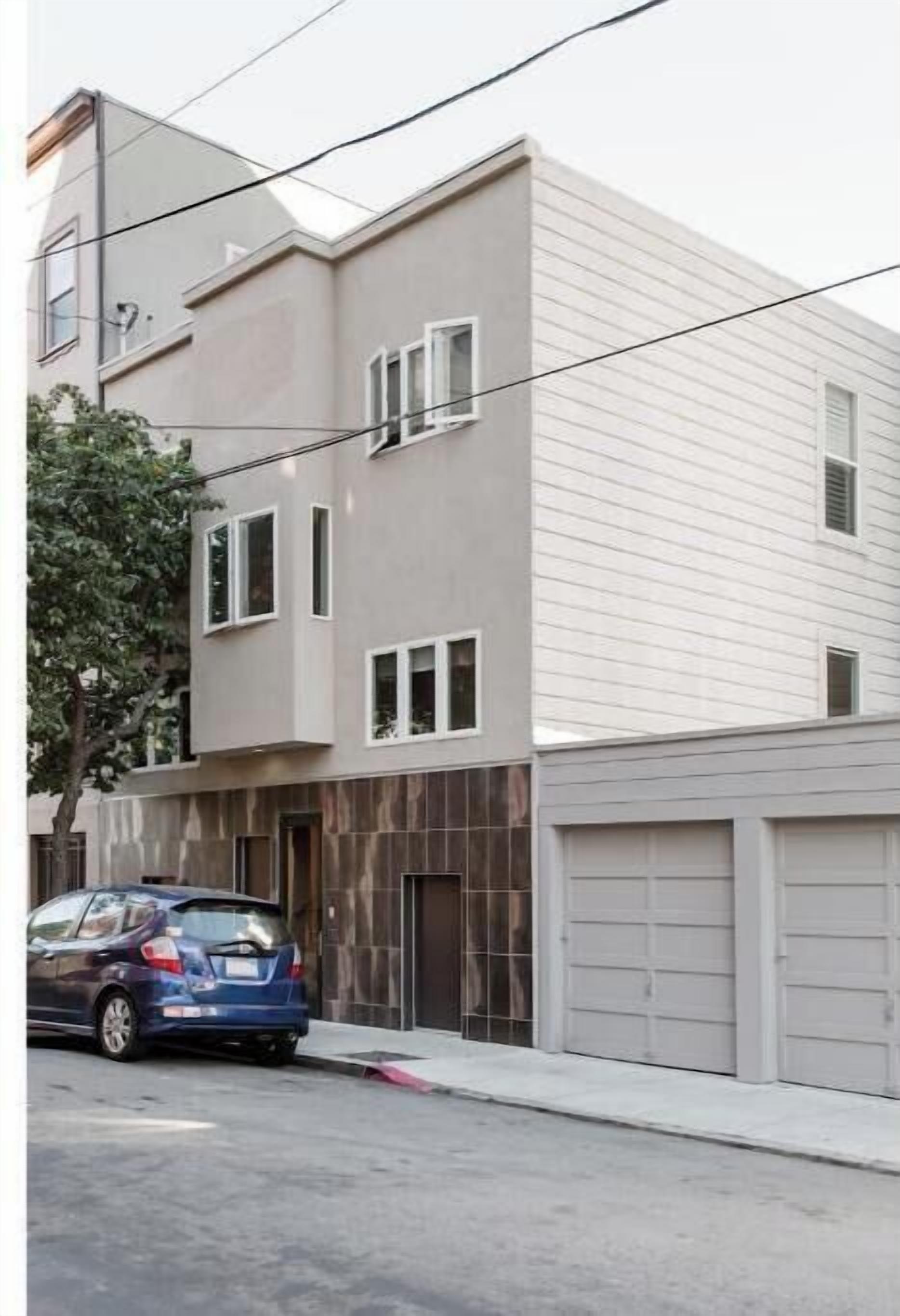 A two-story building with a garage and a parked car.