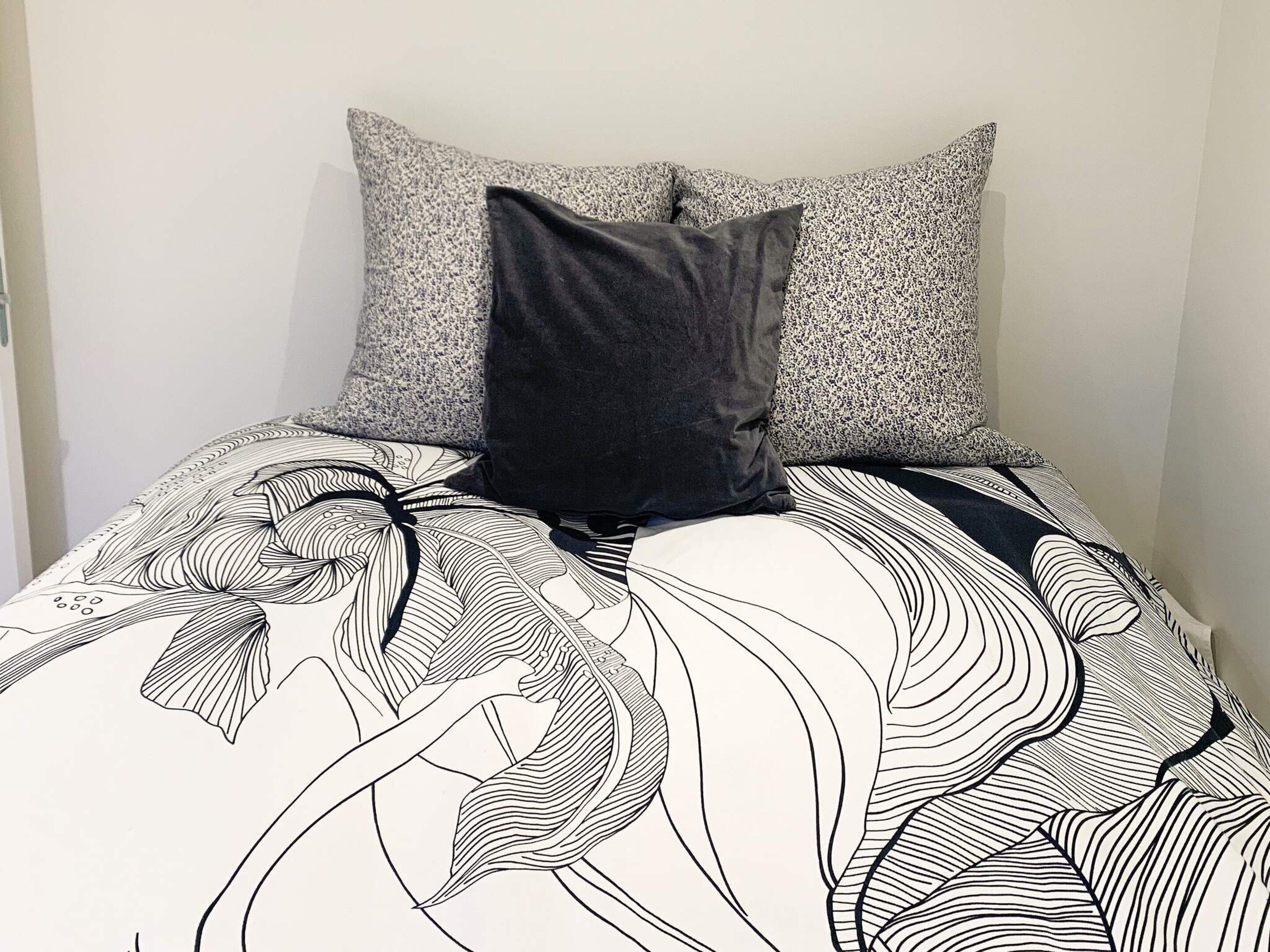 Un lit avec une couvre-lit à motifs et deux oreillers, dont l’un est à pois et l’autre uni.