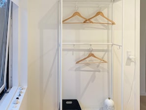 A white closet with two wooden hangers on a rod, a black shelf, and a white decorative item. - 6 Person Holiday Home in Stubbekobing (Stubbekobing)