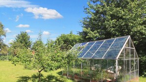 Una serra con tetto trasparente, circondata da vegetazione e alberi.