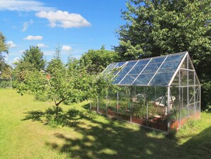 A greenhouse structure with a transparent roof, surrounded by greenery and trees. - 6 Person Holiday Home in Stubbekobing (Stubbekobing)