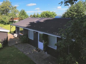 A single-story house with a dark roof, a small porch, and a visible air conditioning unit. - 6 Person Holiday Home in Stubbekobing (Stubbekobing)