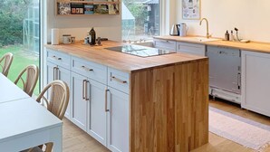 Una cucina moderna con isola centrale, mobili bianchi e vista sull'esterno.