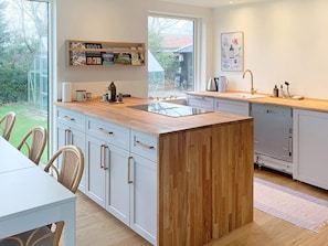 A modern kitchen with a central island, white cabinetry, and a view of the outdoors. - 6 Person Holiday Home in Stubbekobing (Stubbekobing)