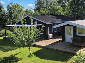 A single-story house with a sloped roof, a front porch, and a small deck area. - 6 Person Holiday Home in Stubbekobing (Stubbekobing)