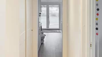 A hallway leading to a room with a sliding glass door, a white wardrobe, and a door with a handle.