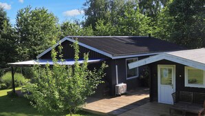 A small house with a sloped roof, a front porch, and a small deck. - 6 Person Holiday Home in Stubbekobing (Stubbekobing)