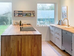 A modern kitchen with a wooden countertop, a built-in oven, and a window with a view of greenery. - 6 Person Holiday Home in Stubbekobing (Stubbekobing)